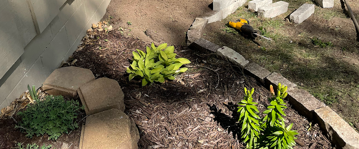 Hardscapes-1 Signature lawns using bricks and stones to create edging for a flower bed.