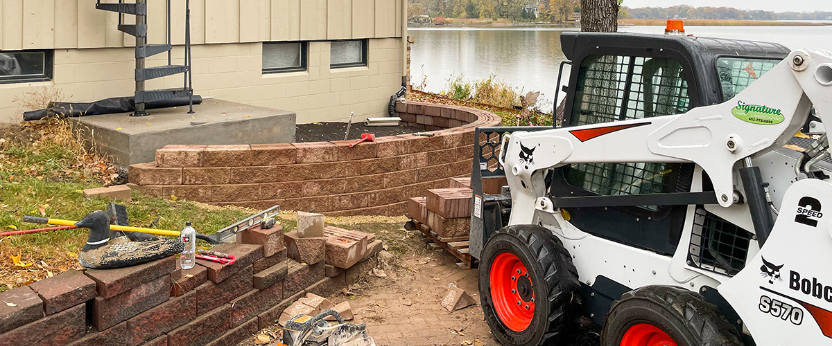 Hardscapes-4 Signature lawns building a retaining wall around a flower bed at a lakeside home.