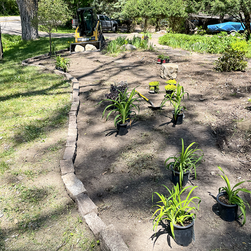 Lawn-Maintenance-5 Some green potted plants being added to a large flower bed