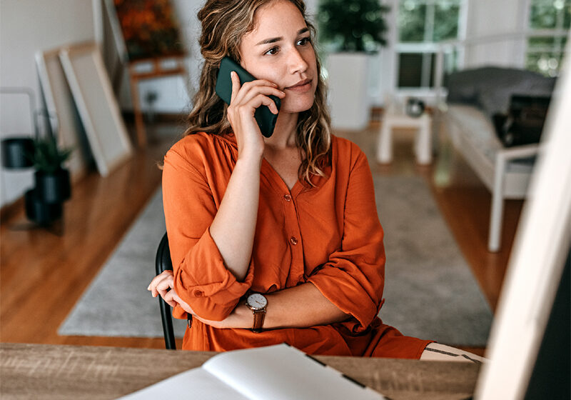 Young woman sitting at a desk on her iphone